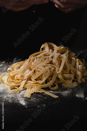 Chef hands making spaghetti, pasta, noodles with fresh pasta on black table with.