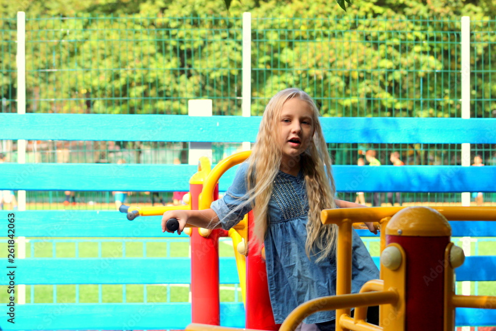 A girl with wavy light long hair looks in a telephone plays him, selective focus. A girl with wavy light long hair looks in a telephone plays him, selective focus.