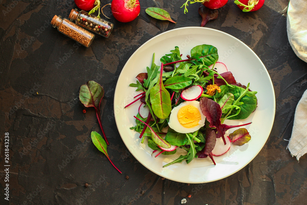 salad with radishes, boiled egg and mix lettuce leaves, appetizer, snack. food background. top view