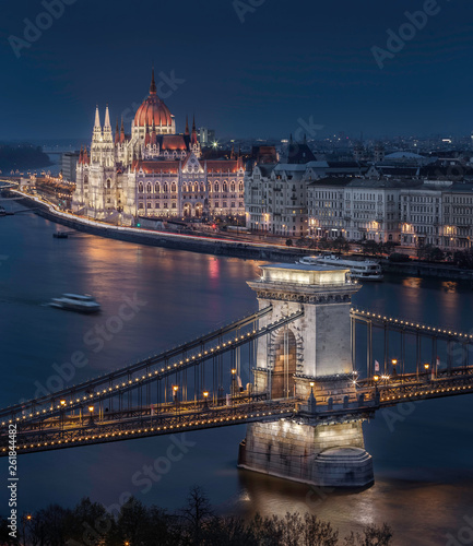 Budapest, Hungary - Beautiful illuminated Szechenyi Chain Bridge with the Parliament of Hungary at blue hour with sightseeing boat on River Danube