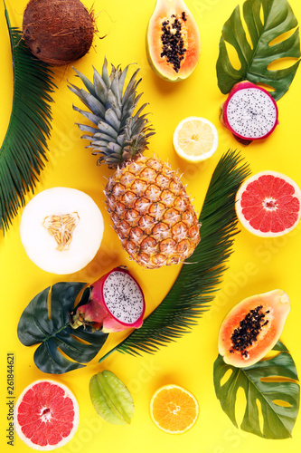 Fototapeta Naklejka Na Ścianę i Meble -  Exotic fruits and tropical palm leaves on pastel yellow background - papaya, mango, pineapple, banana, carambola, dragon fruit