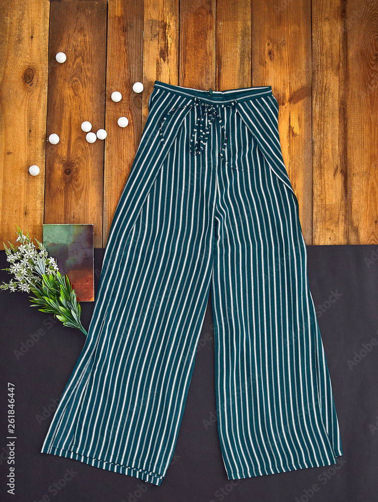 Beautiful unusual outfit presentation for fashion blog, advertising,  clothing catalog. Light summer pants with vertical stripes. Cute pajama  pants. A bouquet flowers and book for romantic atmosphere. Stock Photo