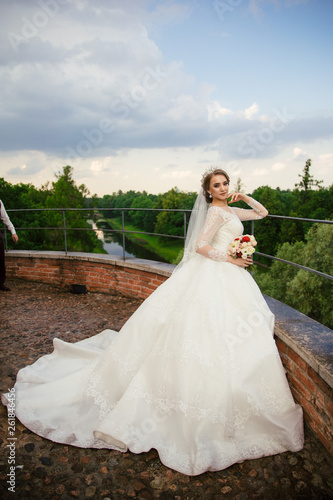 Beautiful Bride in a white Wedding Dress outdoors with a Bouquet of flowers and a veil