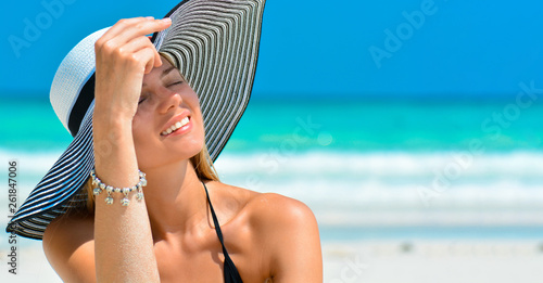Fit smiling girl on a tropical beach with hat. Sexy woman with hat on paradise tropical beach. Beautiful fit body girl on travel vacation. Banner crop for copy space.