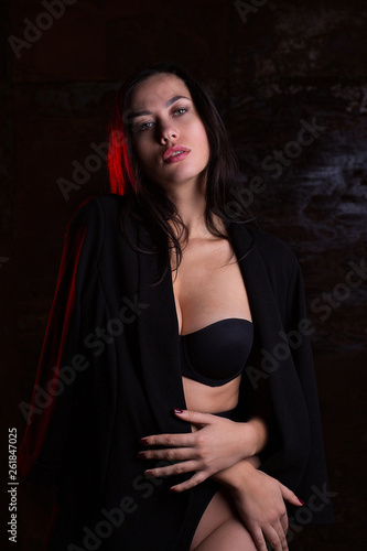 Amazing brunette girl wearing black lingerie posing with red light in the dark