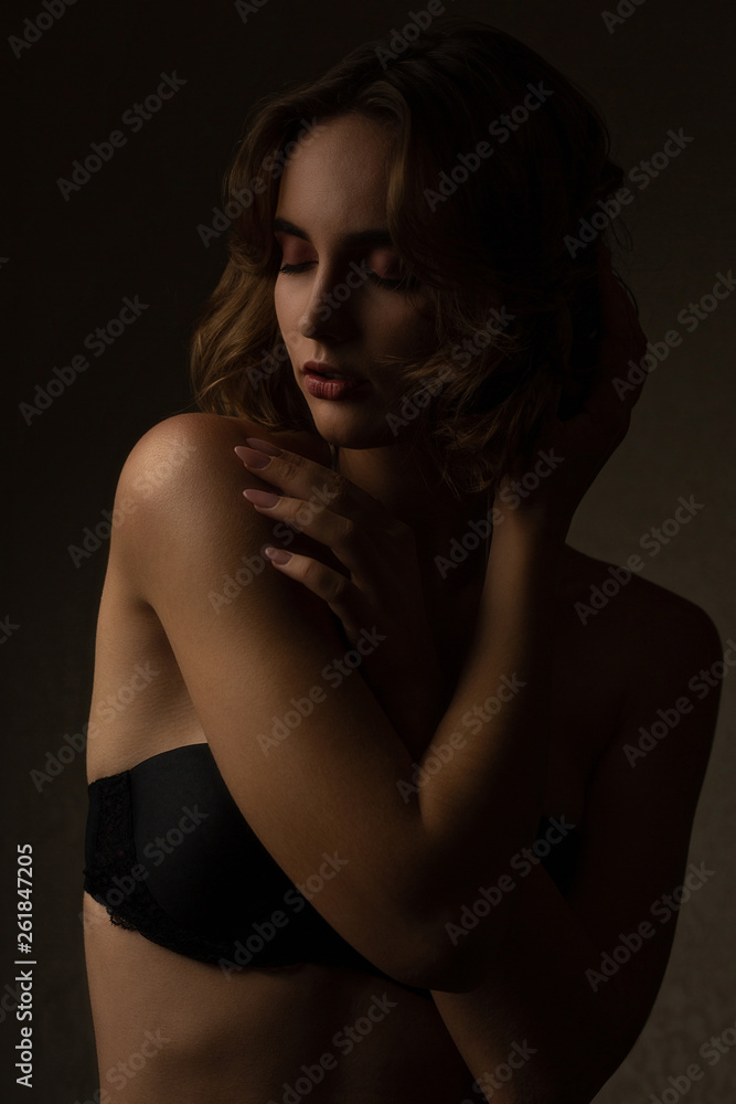 Sexy brunette woman with curly hair wearing bra posing with contrast light Sexy brunette woman with curly hair wearing bra posing with contrast light