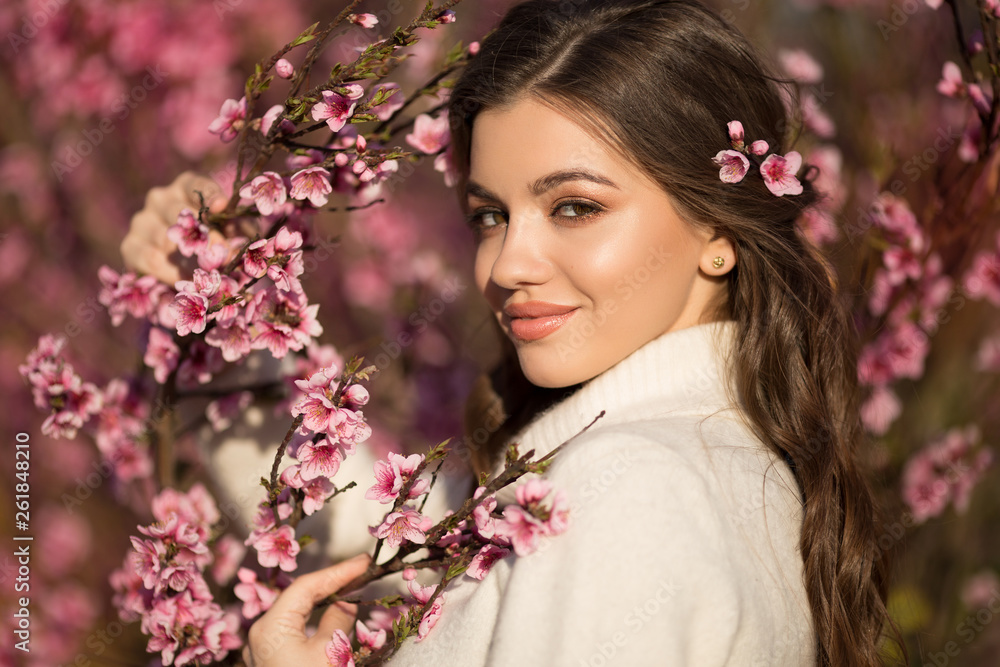 Pretty smiling teen girl posing near blossom cherry tree with pink flowers. Pretty smiling teen girl posing near blossom cherry tree with pink flowers.