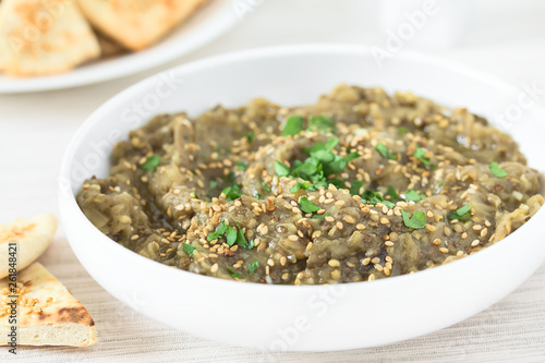 Homemade roasted eggplant dip or spread, baba ganoush in the Mediterranean cuisine, with olive oil, sesame and parsley on top, photographed with natural light (Selective Focus one third into the dip)