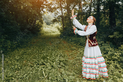 A woman in traditional embroidered Turkic Eastern clothes performs a national dance in the Park photo