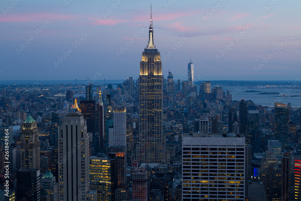 New York City. Manhattan downtown skyline with illuminated Empire State Building and skyscrapers at sunset.