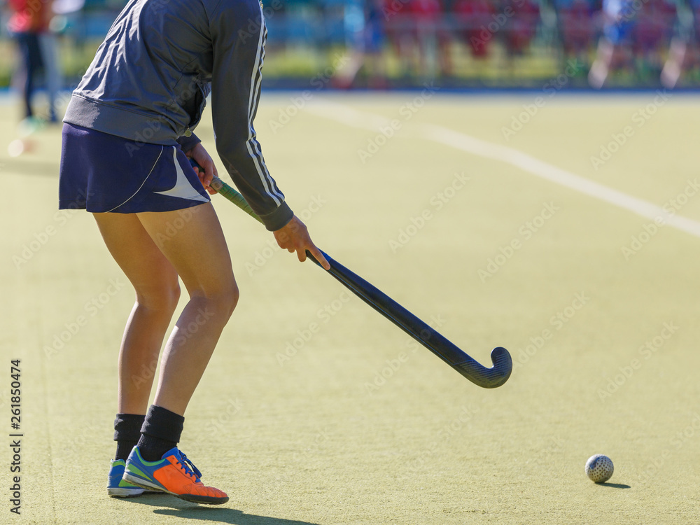Sportswoman with stick and ball on field hockey training