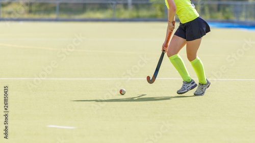 Young female field hockey player leading ball in attack.