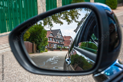 Looking through the car mirror to the traditional half-timbered houses in the streets of the small town of Seebach in Alsace, France © Sergey Kelin