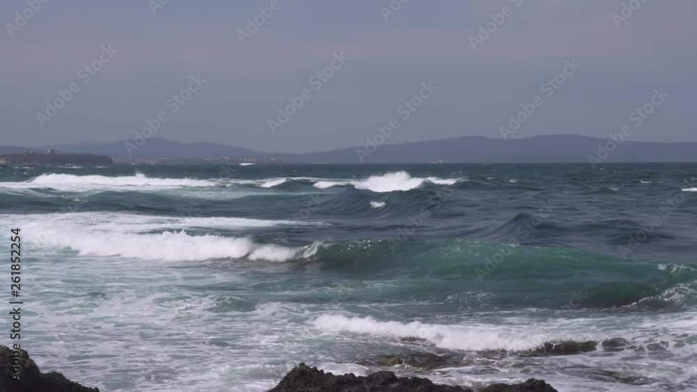 Panning right to left shot of big Black Sea foamy waves breaking near rocky shore in Lozenets, Bulgaria at daytime Panning right to left shot of big Black Sea foamy waves breaking near rocky shore in Lozenets, Bulgaria at daytime