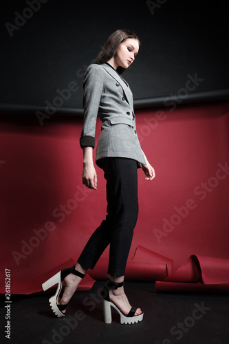 Young beautiful female fashion model in a business stylish suit on a red and black background.