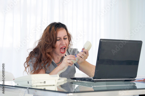 Close-up woman office worker swears with the client by phone. A woman is shouting into the phone s phone. Funny facial expressions  emotions  reaction of perception  stress  gilding  nerves.