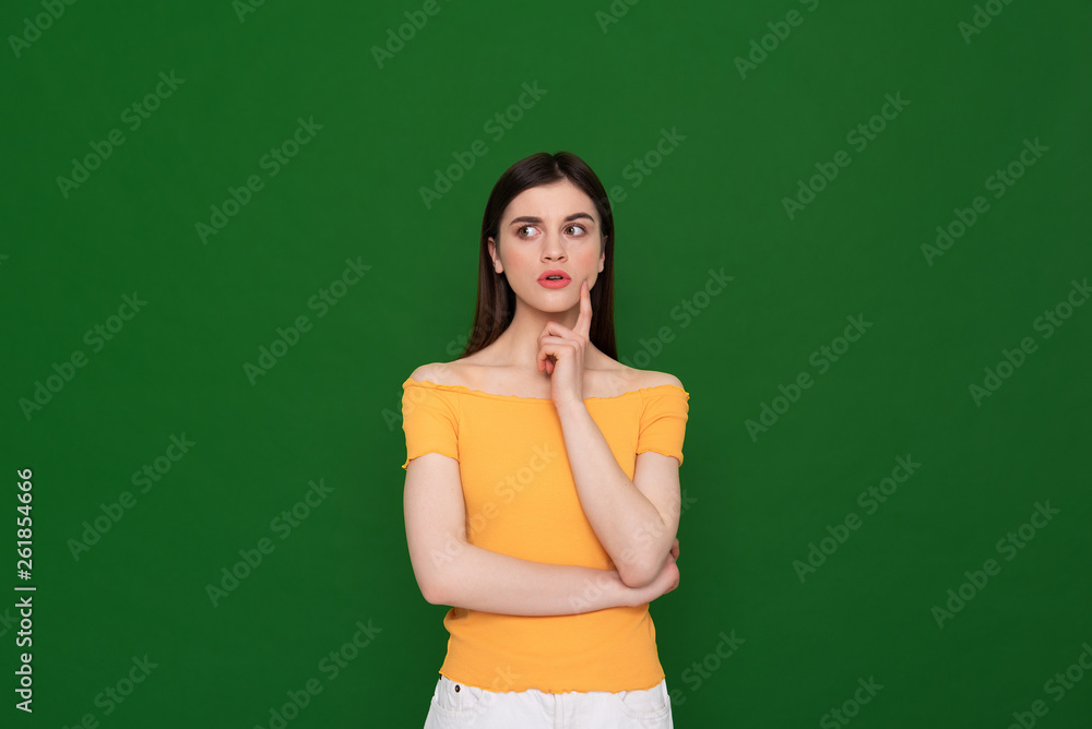 Thoughtful pretty young girl isolated on green Thoughtful pretty young girl isolated on green