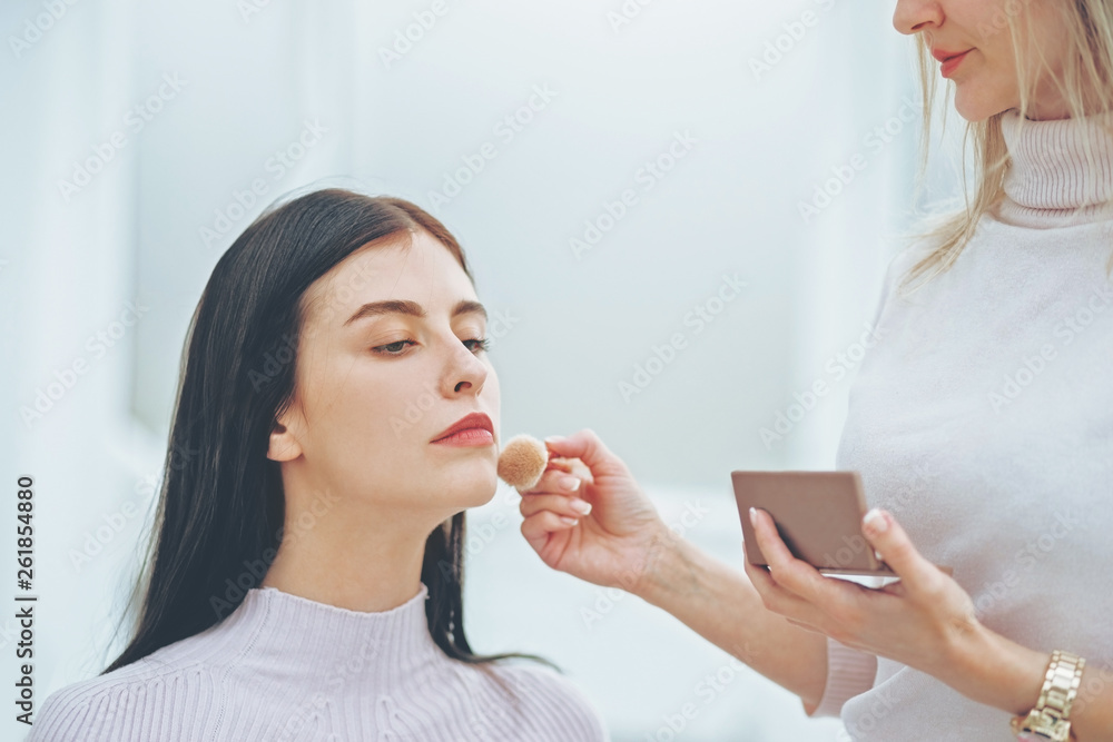 make up artist doing professional make up of young woman