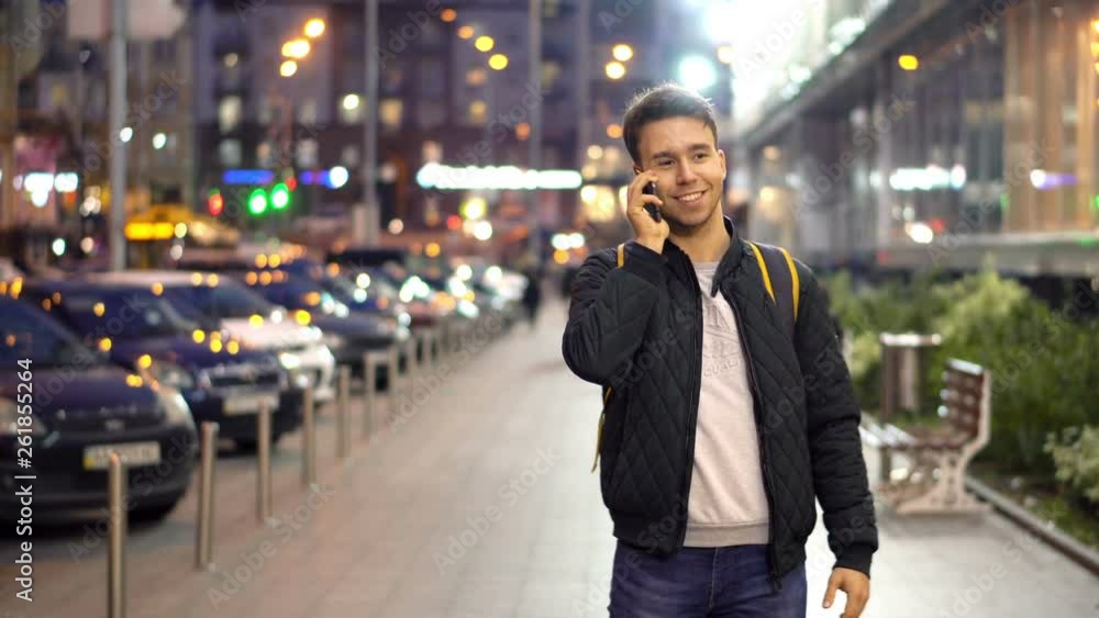 Young Attractive Man Speaking by Phone in the evening city street with bokeh light effect Young Attractive Man Speaking by Phone in the evening city street with bokeh light effect