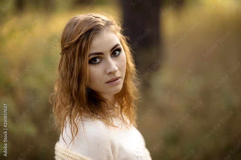 red-haired girl in bright clothes on a background of autumn forest on a sunny day