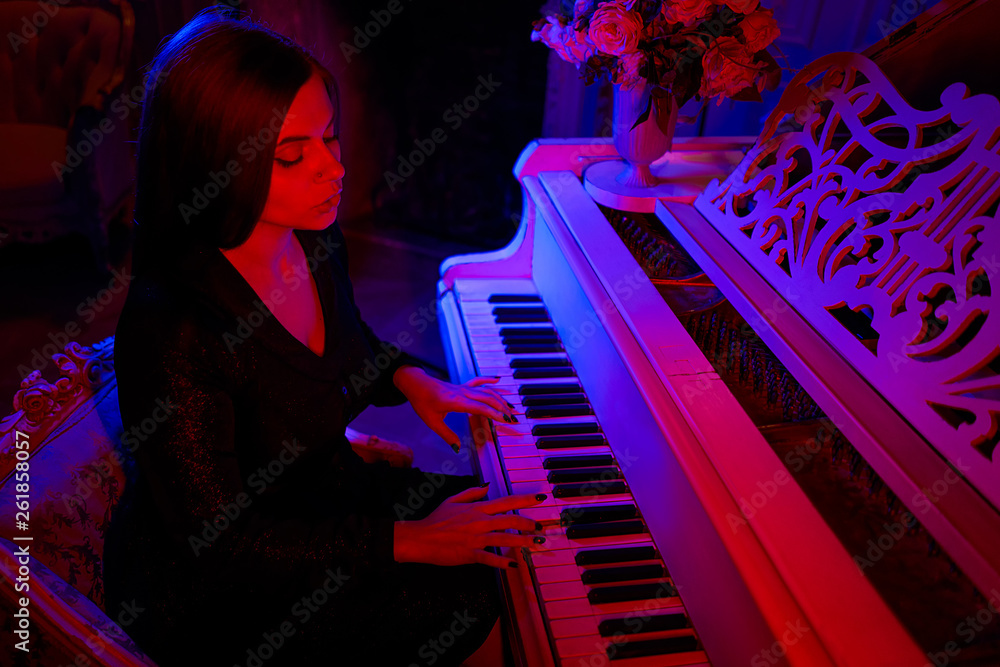 Beautiful girl and grand piano under the light of multi-colored lamps.  Fantastic atmosphere of unusual colors. pianist girl playing a musical  instrument piano in a dark room Stock Photo | Adobe Stock