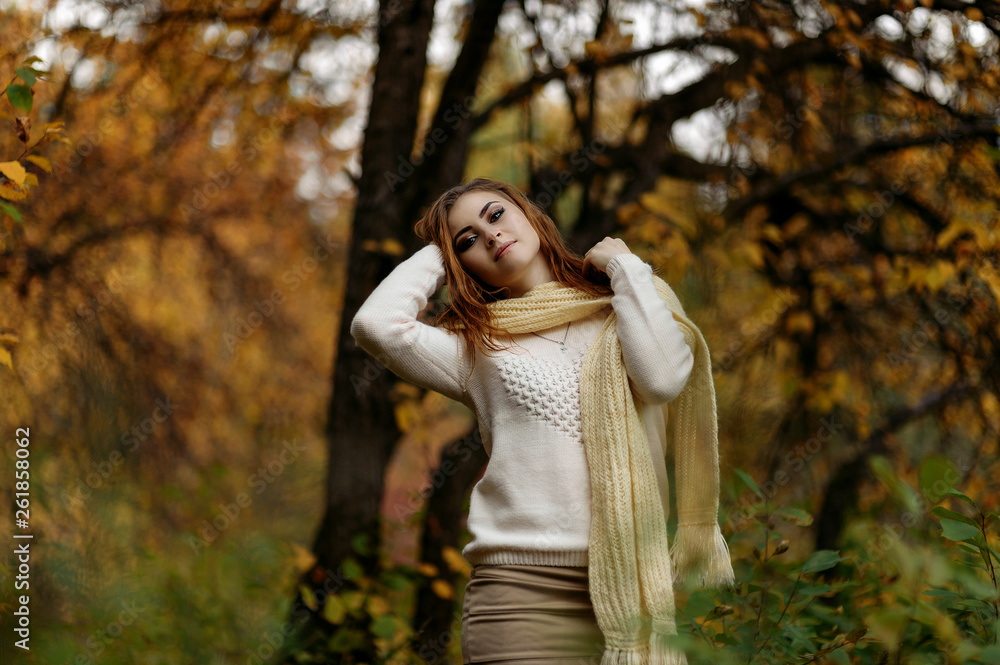 red-haired girl in bright clothes against a background of tree trunks in the autumn forest red-haired girl in bright clothes against a background of tree trunks in the autumn forest