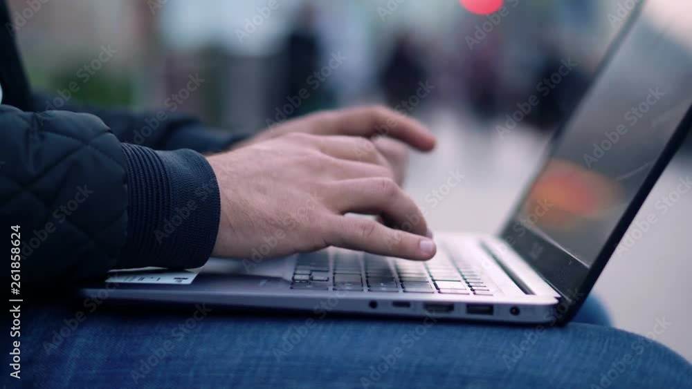 Close-up View of Man Using Laptop in the city street with bokeh effect Close-up View of Man Using Laptop in the city street with bokeh effect