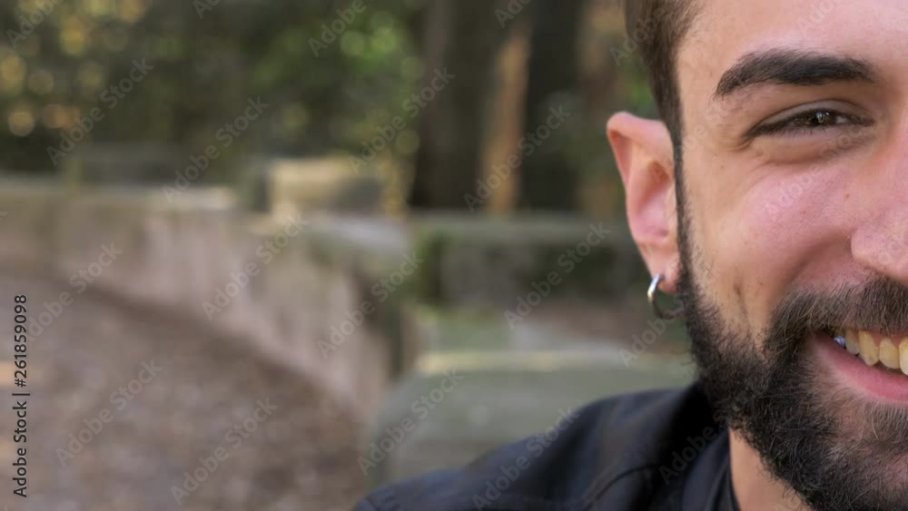 Handsome young man smiling at camera in the park-half face Handsome young man smiling at camera in the park-half face