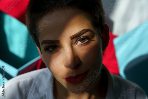young beautiful brunette woman sit on bed at home among colour red and blue cases © Alexander