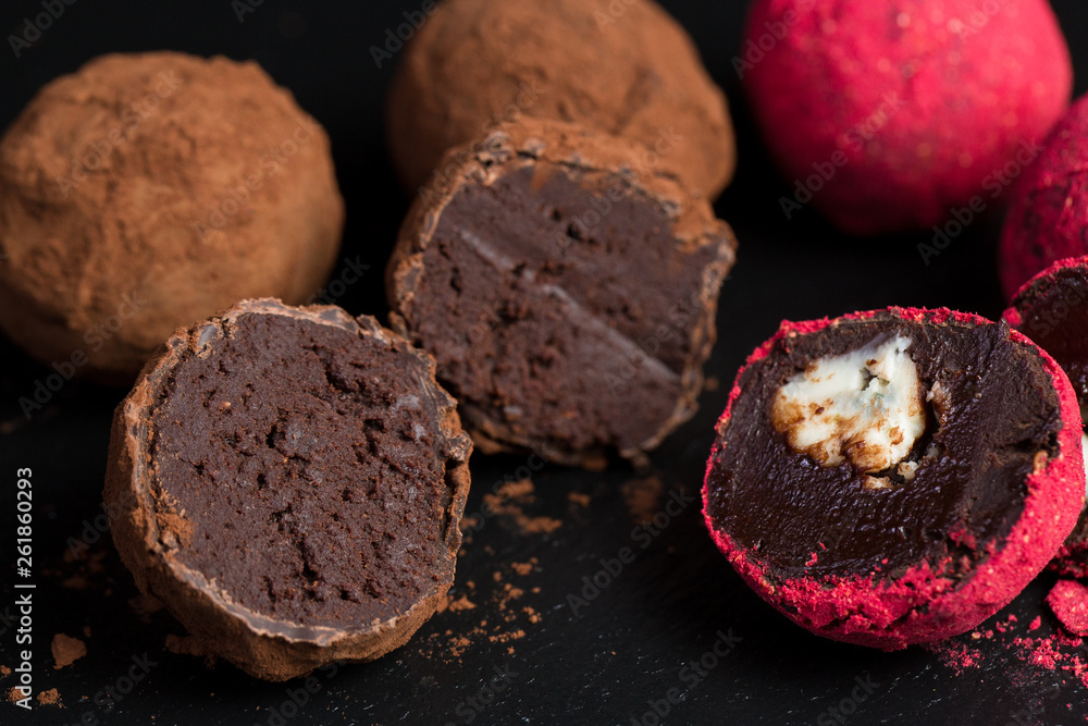 Theme sweet dessert cake handmade. Macro close-up dessert sweet candy round ball truffle set of black chocolate cocoa raspberry puer on a black background Theme sweet dessert cake handmade. Macro close-up dessert sweet candy round ball truffle set of black chocolate cocoa raspberry puer on a black background