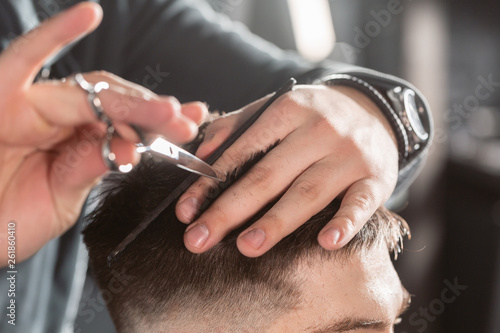 Close-up Hair cutting with metal scissors. Master cuts hair and beard of men in the barbershop, hairdresser makes hairstyle for a young man