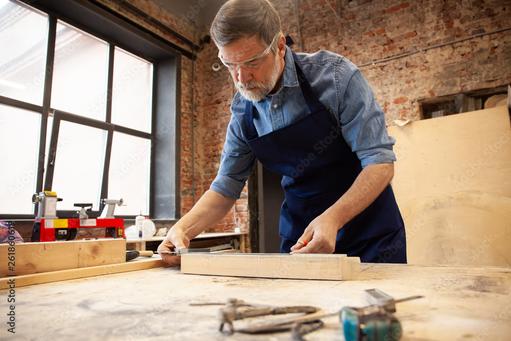 Mature handsome joiner work in carpentry. He is successful entrepreneur at his workplace. Mature handsome joiner work in carpentry. He is successful entrepreneur at his workplace.