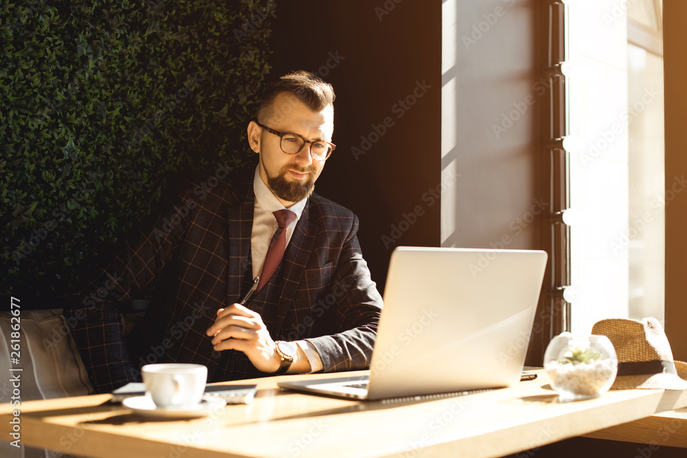 Young businessman working on a plan of Internet project on the laptop. Man discusses business matters by phone. Working computer for internet research. Digital marketing. Development Young businessman working on a plan of Internet project on the laptop. Man discusses business matters by phone. Working computer for internet research. Digital marketing. Development