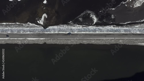 Bird's Eye View of a Car Driving Along a Narrow Road Crossing a Lake photo