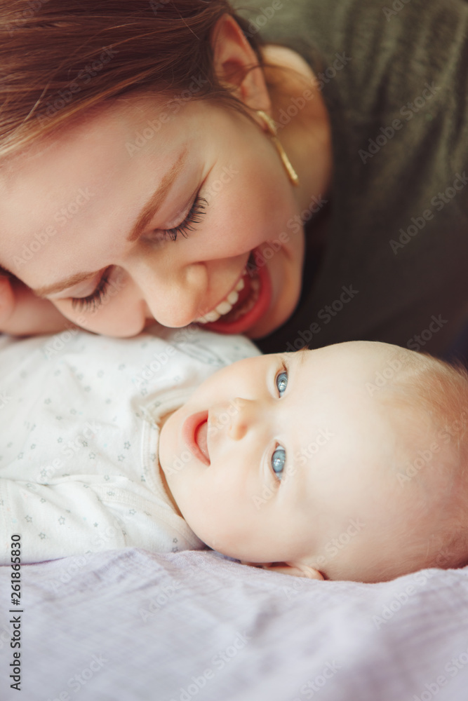 Closeup of young Caucasian woman mother hugging kissing playing with cute newborn baby boy girl child at home. Authentic candid family lifestyle. Happy motherhood and parenting. Closeup of young Caucasian woman mother hugging kissing playing with cute newborn baby boy girl child at home. Authentic candid family lifestyle. Happy motherhood and parenting.