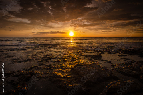 Golden sunset refelcts over the ocean waves in the lush sandy Tamarindo area of Costa Rica that is frequently visited by tourists on vation to this tropical region photo