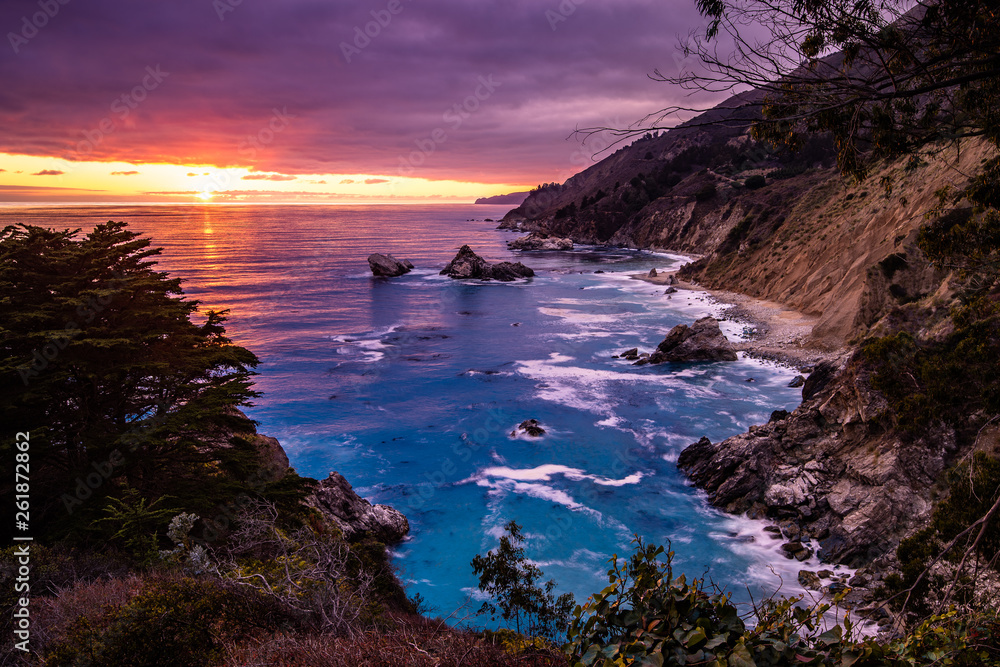 Dramatic Big Sur sunset on the West coast near Monterey California. The awesome sunset contrasts the turquoise blue waters of the bay.