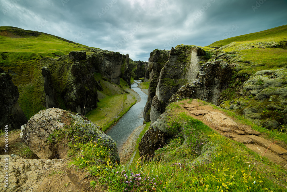 Fjaðrárgljúfur canyon in Iceland is captured during soft light conditions. The natural Icelandic landscape of the canyon looks like a majestical fantasy brimming with a natural romantic aura.
