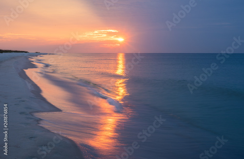 Amazing pink sunrise at Orange beach in Gulf Shores Alabama. The white sands and emerald waters take a whole new look during sunrise and sun set under unique weather and cloud conditions.