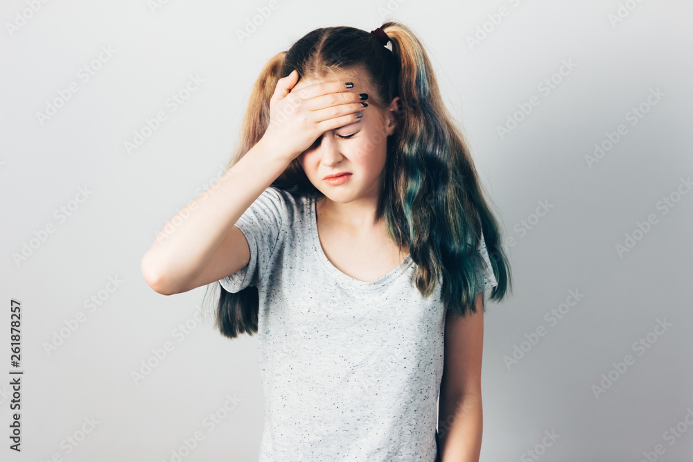 A girl with a headache holding her hand to the head. Gray studio background. A girl with a headache holding her hand to the head. Gray studio background.