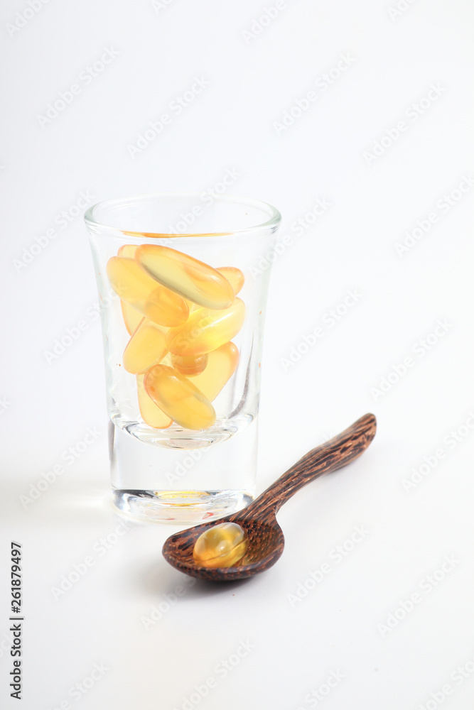 Cod liver oil omega 3 gel capsules on a wooden spoon object with glass medicine on white background Cod liver oil omega 3 gel capsules on a wooden spoon object with glass medicine on white background