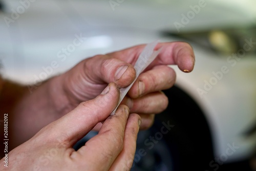 Close up of hands rolling a joint in front of a car. Concept of impaired driving