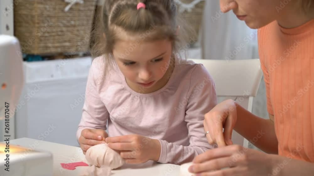 Mother teaching her little daughter to sew using needle and thread in the nursery at home. Children's craft, education and training Mother teaching her little daughter to sew using needle and thread in the nursery at home. Children's craft, education and training