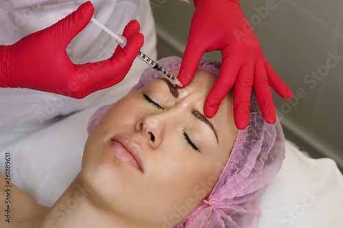 Hands cosmetologist injections in face of girl. Young woman gets beauty injections in spa salon. Medical procedures smoothing mimic wrinkles. Anti-aging injections of collagen acid