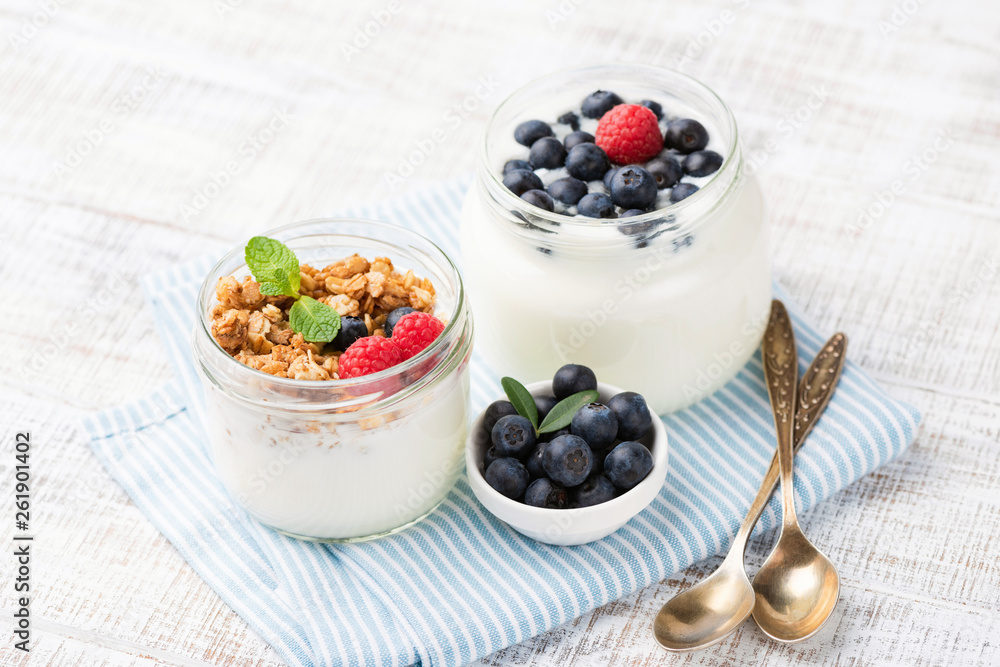 Greek yogurt with berries and granola cereals in jar on blue checkered napkin. Food for dieting, weight loss, healthy lifestyle, healthy breakfast or snack Greek yogurt with berries and granola cereals in jar on blue checkered napkin. Food for dieting, weight loss, healthy lifestyle, healthy breakfast or snack