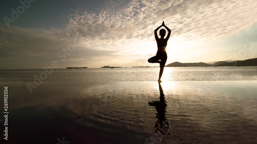 Female tourist exercising yoga on the beach