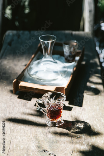 Hot drip coffee in drinking glass on wooden table with harsh sunlight.