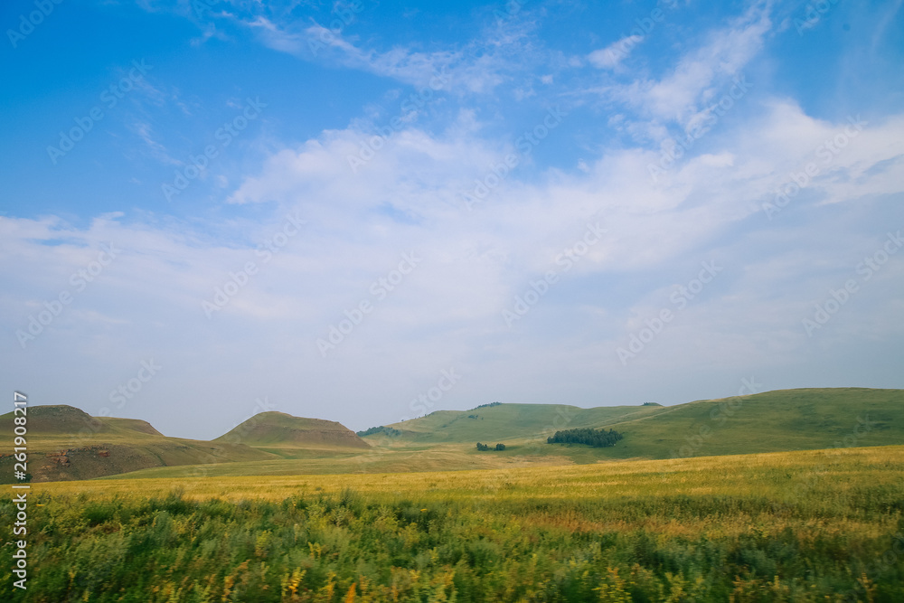 Blue sky with white clouds, green fields and hills