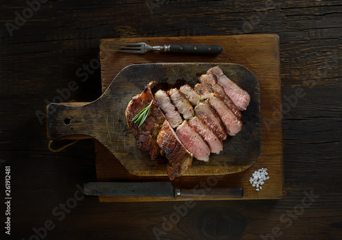 Sliced grilled  barbecue steak   on cutting board on dark wooden background