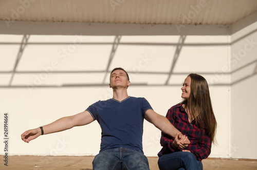 couple guy and girl are sitting on the open stage under the bright rays of the summer sun. close view